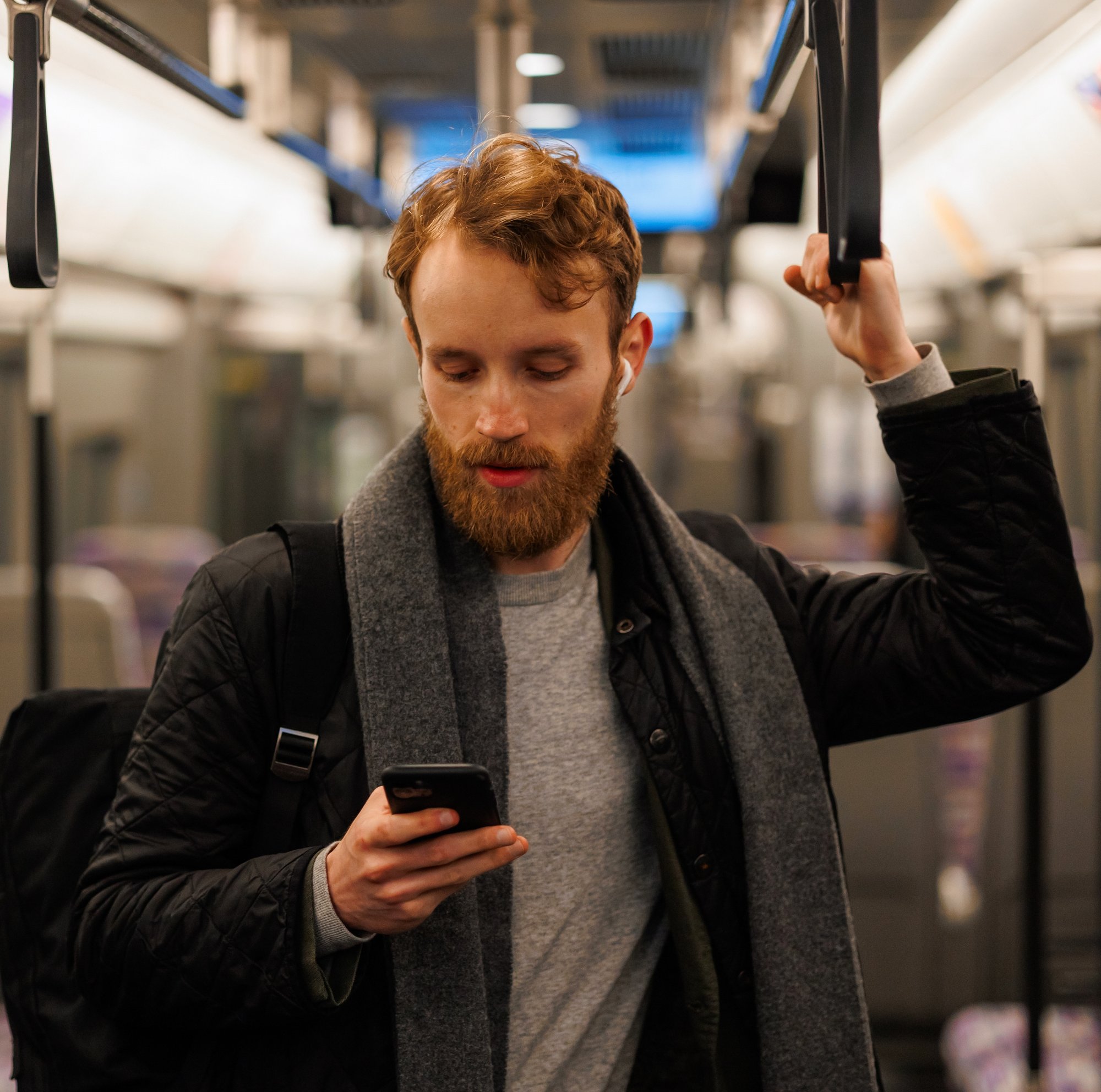 stylishly-dressed-bearded-man-stands-subway-car-headphones-smartphone-his-hand-passenger-public-transport